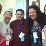 A photograph of five women of various races posing together and smiling.